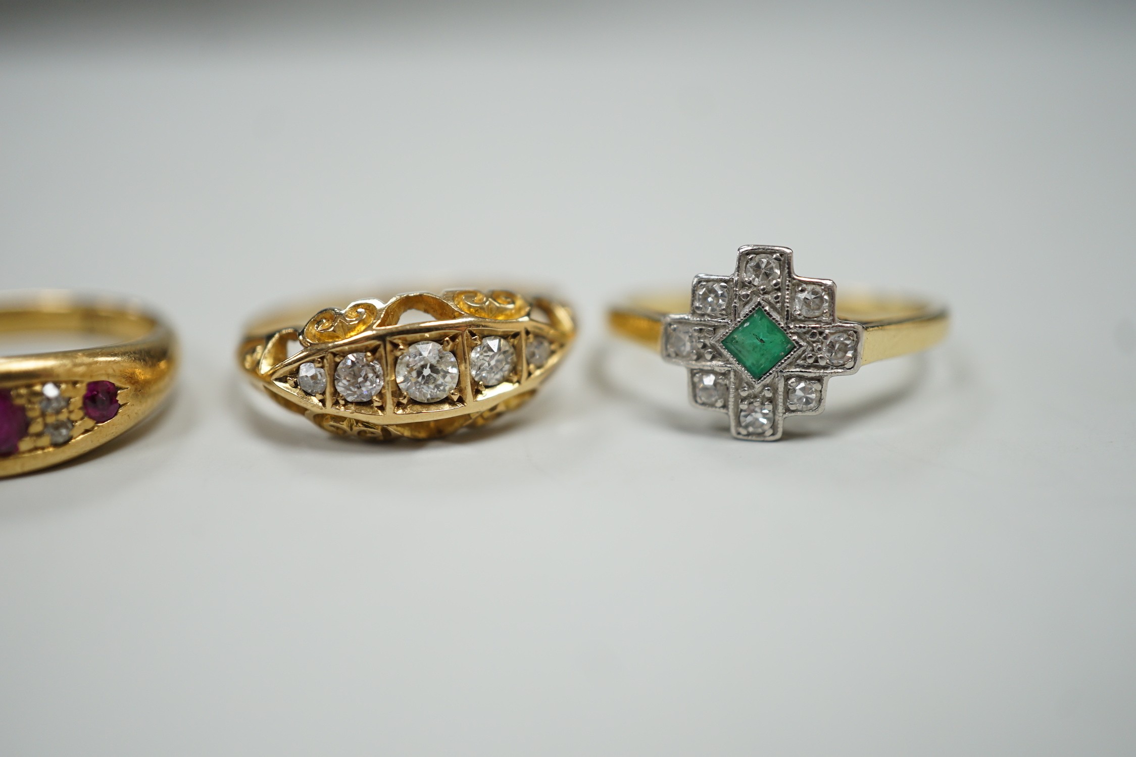 Three early 20th century 18ct and gem set rings, including ruby and diamond chip, size O, graduated five stone diamond, size P and an emerald and diamond cluster, size M, gross weight 10 grams.